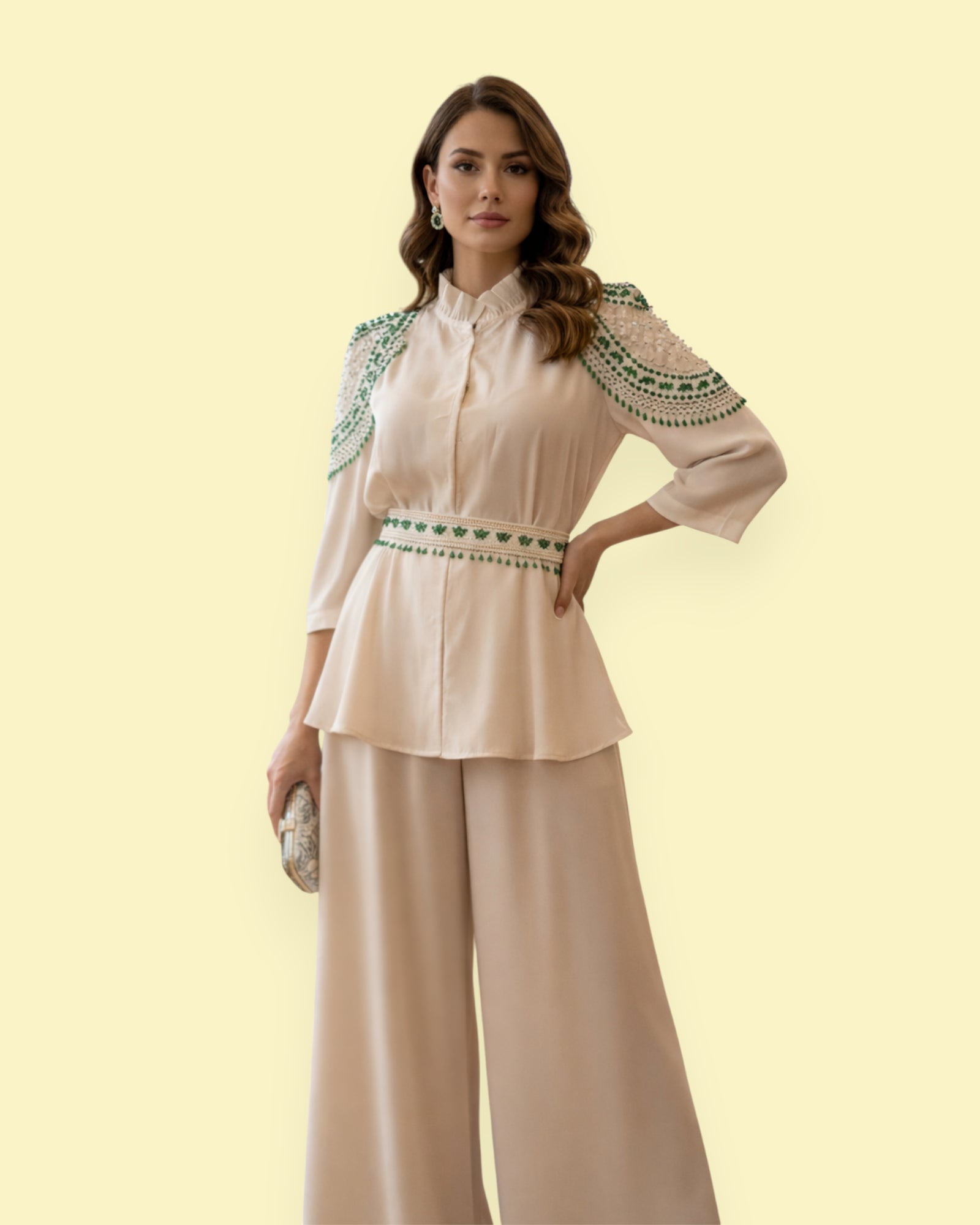 Woman wearing a beige blouse with green embroidery and wide-leg pants on a light yellow background