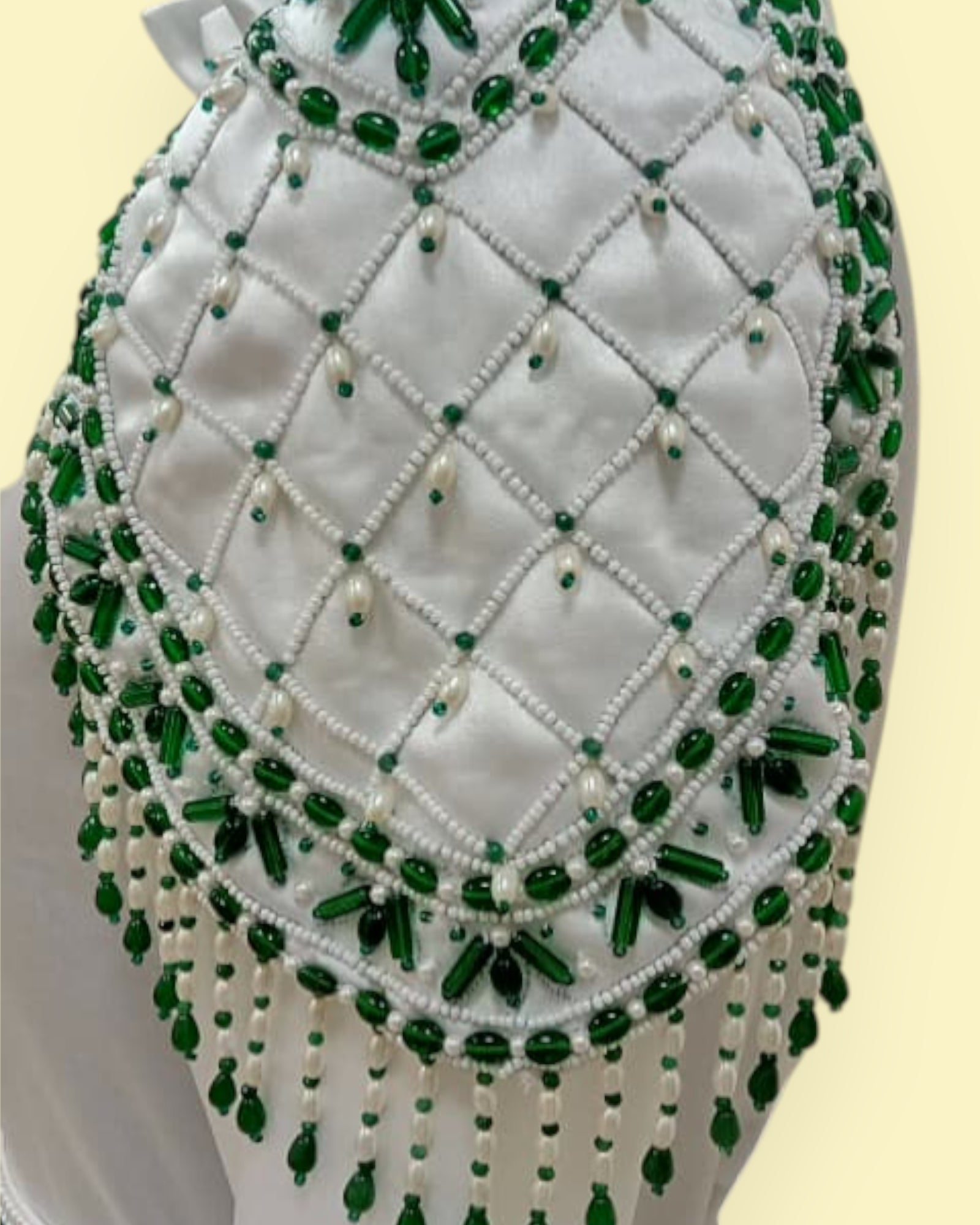 Decorative headpiece with green and white beads on a beige background