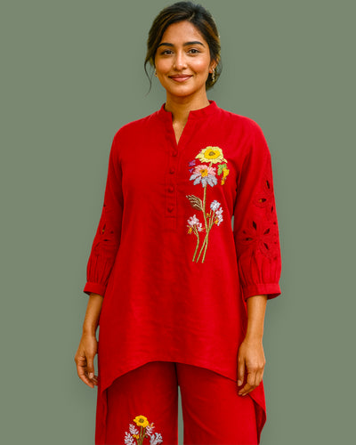Woman wearing a red embroidered outfit on a plain background