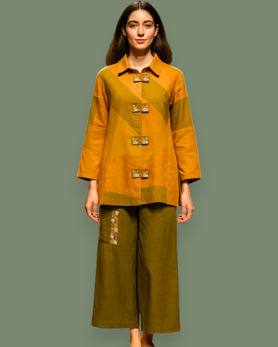 Woman wearing a mustard yellow and green outfit with a plain background