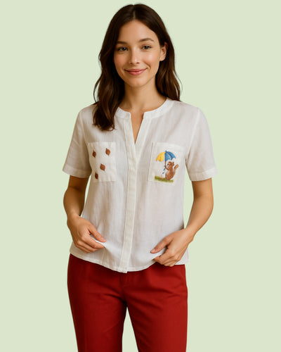 Woman wearing a white shirt with embroidered designs on a light green background