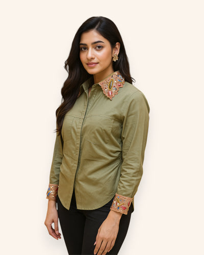 Woman wearing a green shirt with embroidered details on a white background