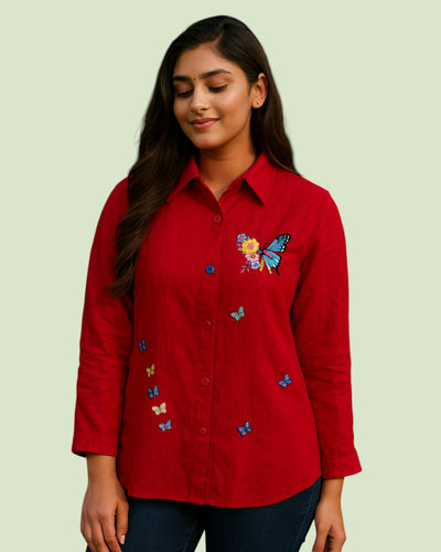 Woman wearing a red shirt with butterfly embroidery designs on a light green background