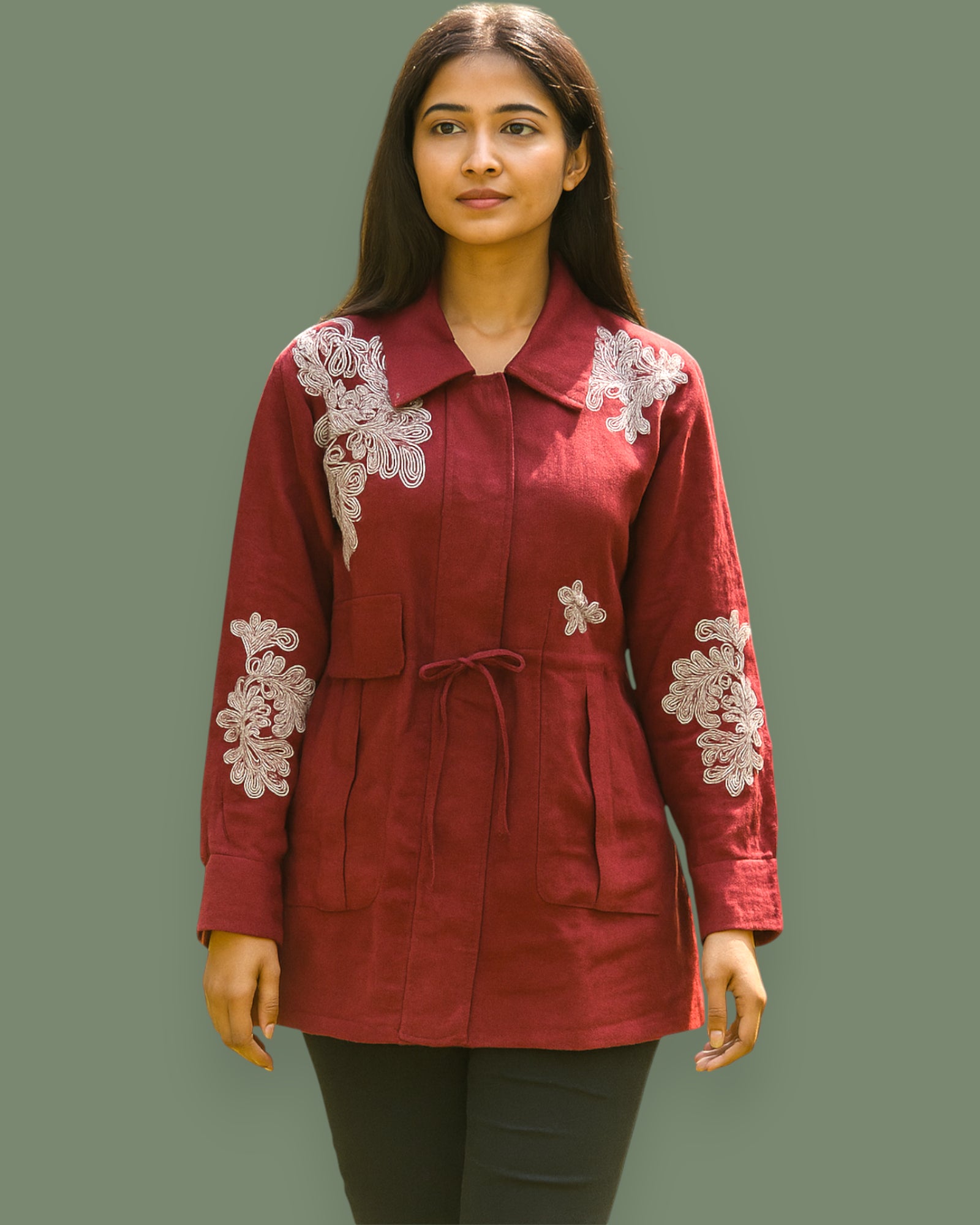 Woman wearing a red jacket with white lace embroidery on a plain background