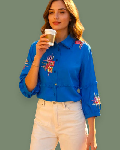 Woman wearing a blue embroidered shirt on a gray background